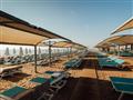 Krásna piesková pláž so slnečníkmi pred hotelom Limak Cyprus
